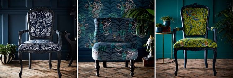 Three elegant chairs with ornate patterns set against dark, richly textured walls and wooden flooring, surrounded by plants and decor.