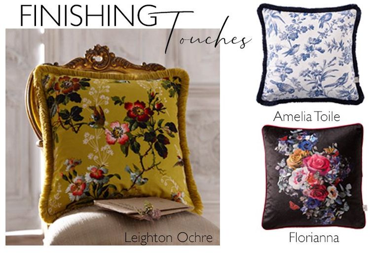 Three decorative pillows: one with yellow floral design, one with blue toile pattern, and one with colorful floral embroidery on black.