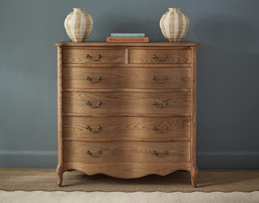 A curved solid wooden chest of drawers with a scalloped base edge and cabriole legs.