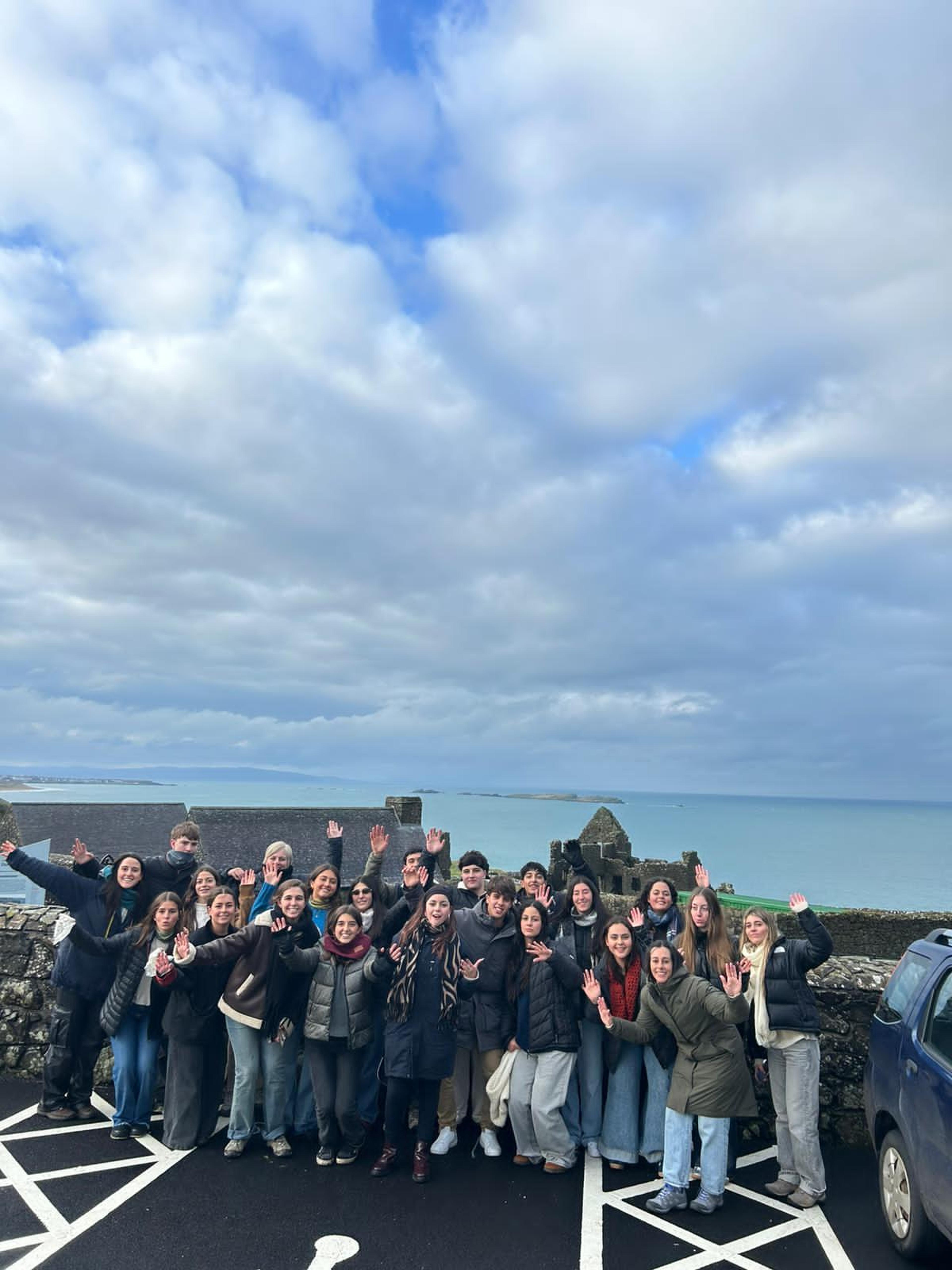 Grupo de estudiantes argentinos durante una excursión educativa en Irlanda, con paisaje costero de fondo.