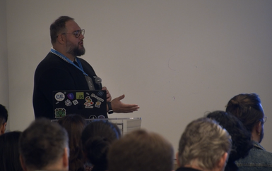 Two presenters from Virgin Media O2 presenting slides and a demo to attendees in a breakout room at JoyConf NY