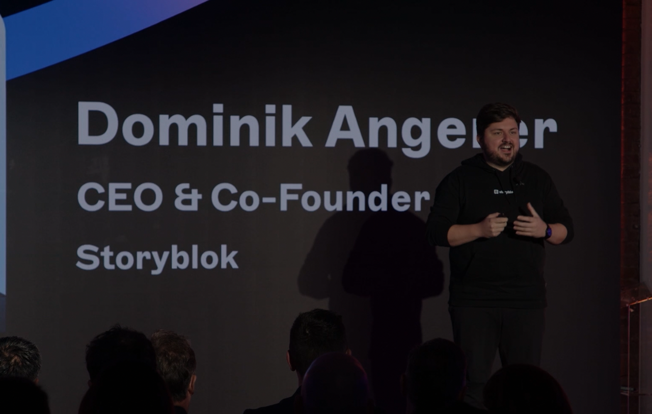 A person speaking on stage with "Dominik Angeler, CEO & Co-Founder, Storyblok" displayed on a screen behind them.