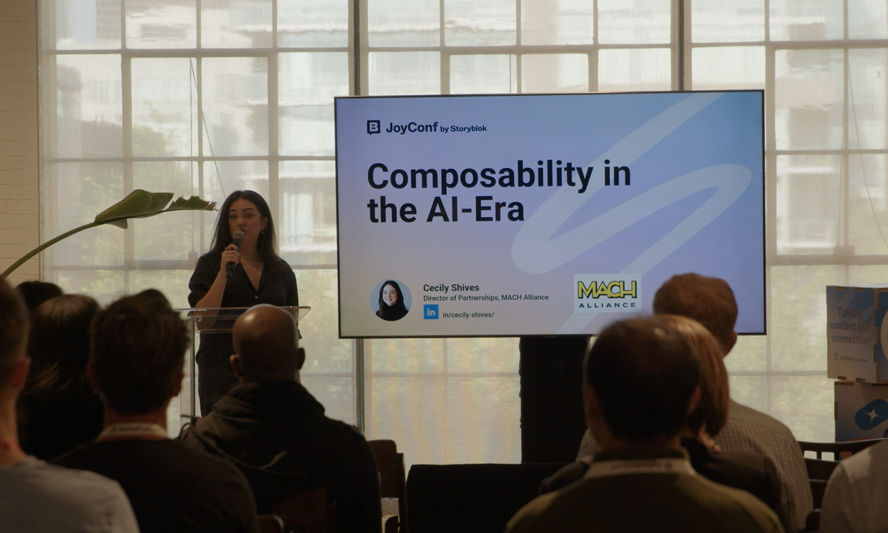 A speaker presents at JoyConf, discussing "Composability in the AI-Era," with an audience seated in a well-lit room.
