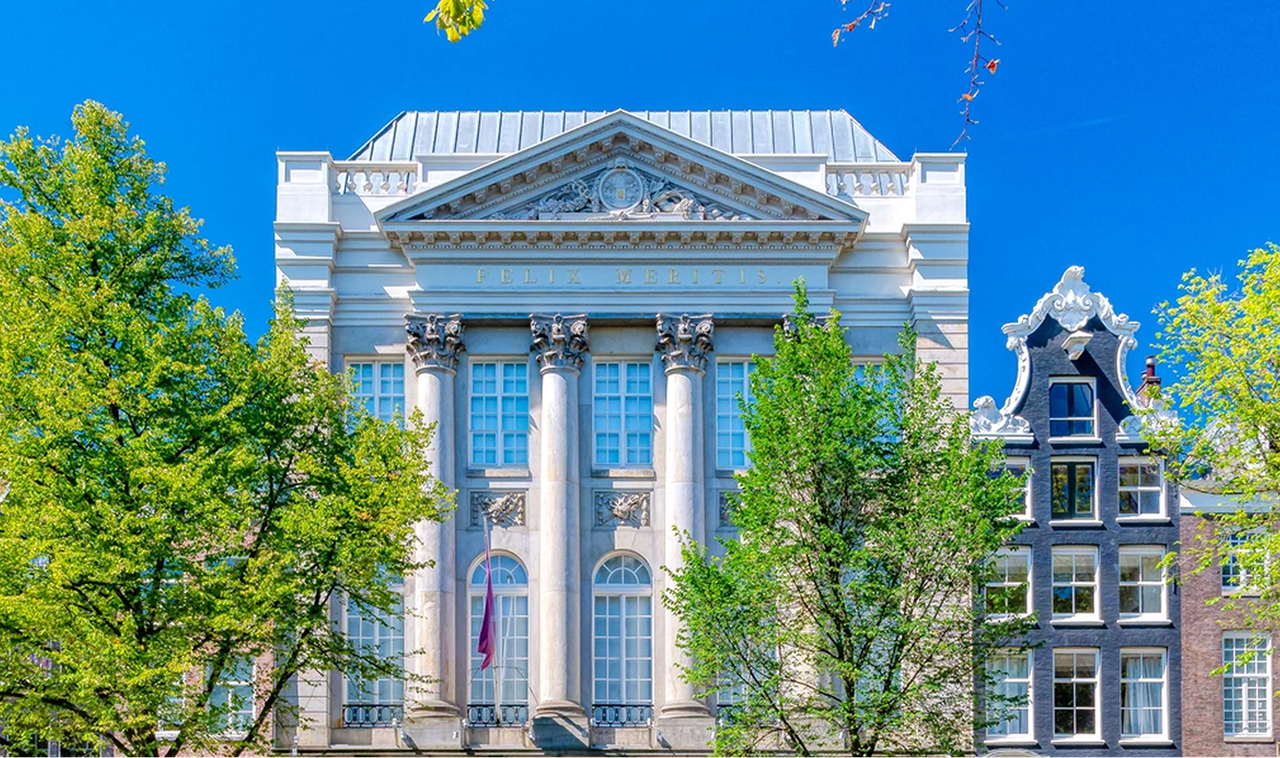 Felix Meritis. A classical tall white building standing on an Amsterdam street by the canal.