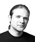 Black and white portrait of a person with long hair tied back, wearing a dark shirt.