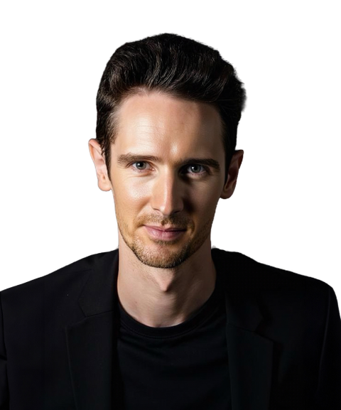 A man with short dark hair wearing a black shirt and jacket against a dark background.