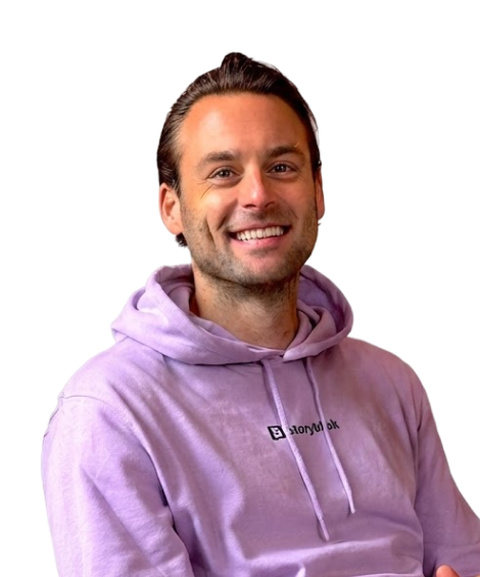 Smiling man in a lavender hoodie, sitting and looking forward.