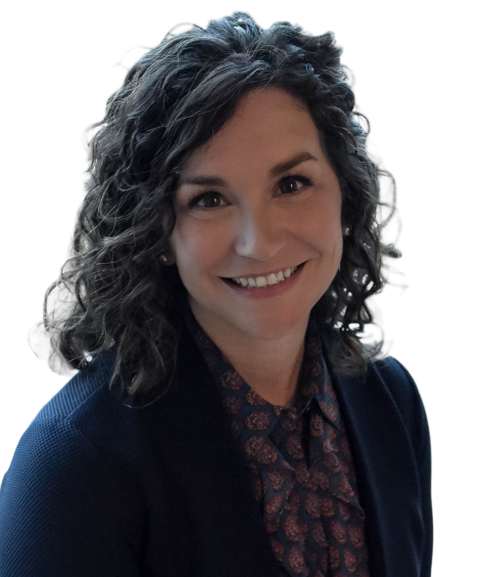 Smiling woman with curly hair wearing a patterned blouse and blazer.