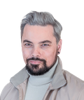 Man with gray hair and beard, wearing a light-colored turtleneck and jacket, smiling slightly against a plain background.