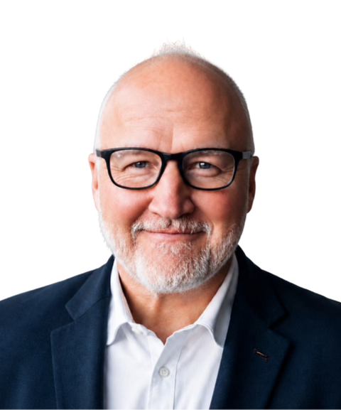 Bald man with glasses and a beard, wearing a dark blazer and white shirt, smiling slightly against a plain background.
