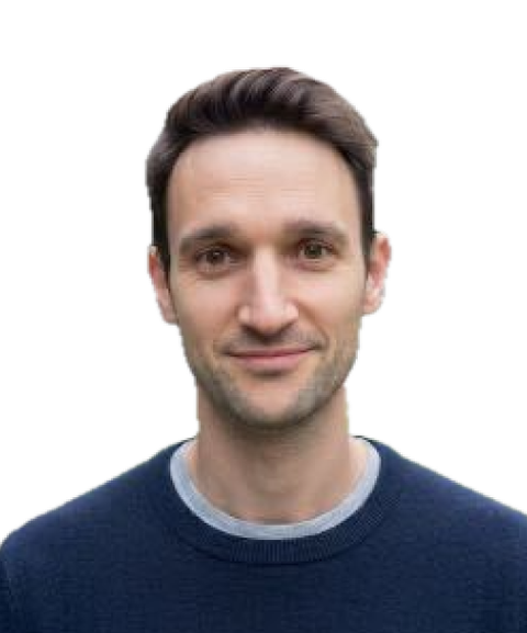 A person with short dark hair wearing a navy blue sweater, smiling slightly, set against a white background.
