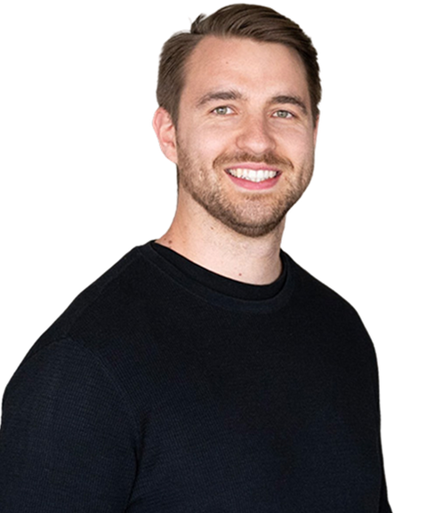 Smiling man with short hair and a beard wearing a black sweater against a plain background.