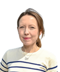 Woman with light brown hair in a ponytail, wearing a striped sweater and necklace, smiles slightly against a plain white background.