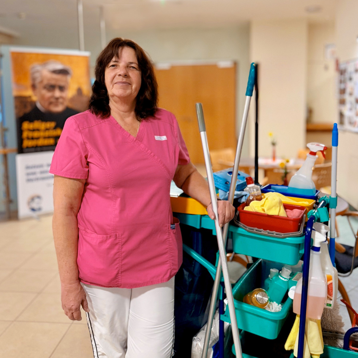 Reinigungskraft in Dienstkleidung mit Reinigungswagen