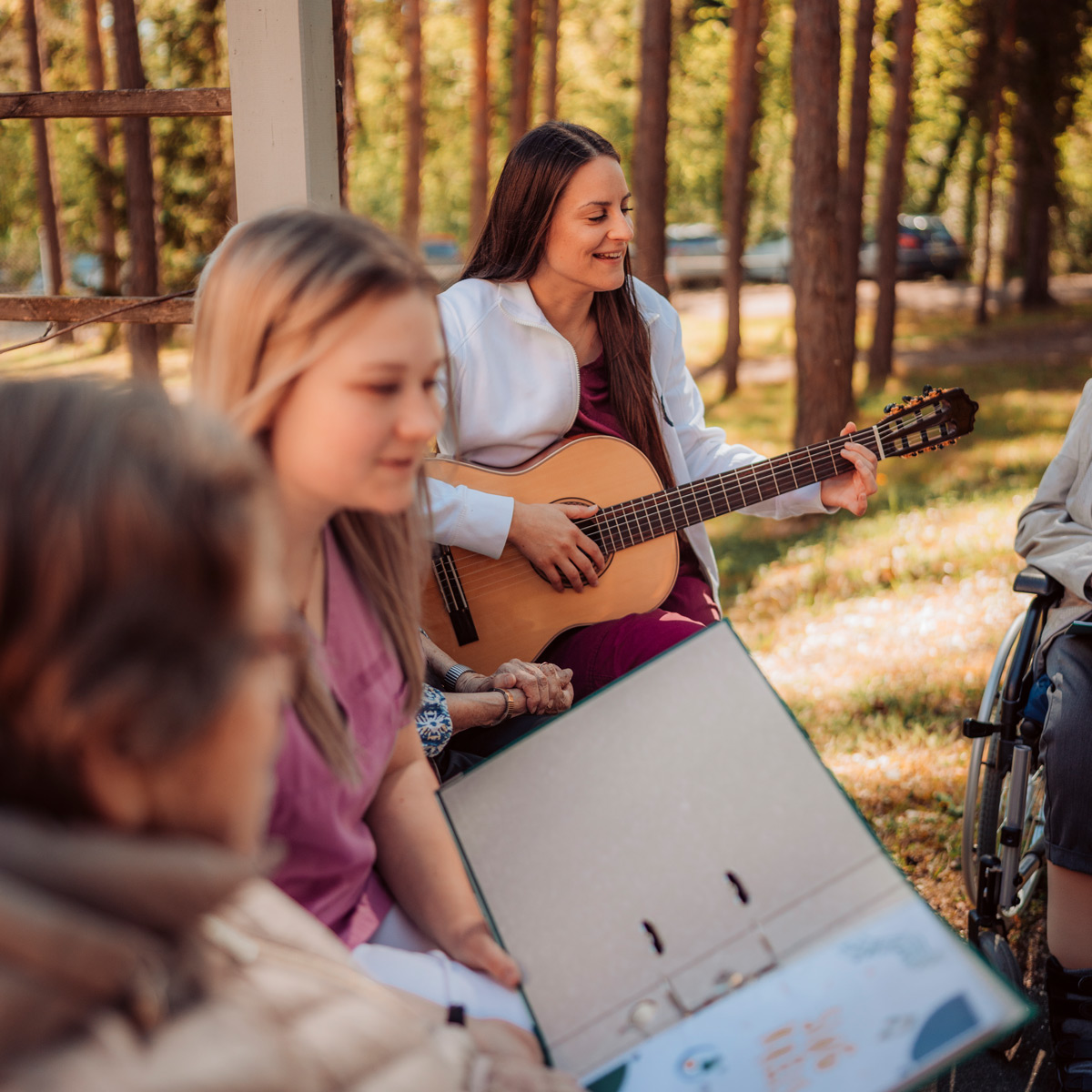 Eine junge Sozialbetreuerin spielt auf der Gitarre, eine Bewohnerin singt