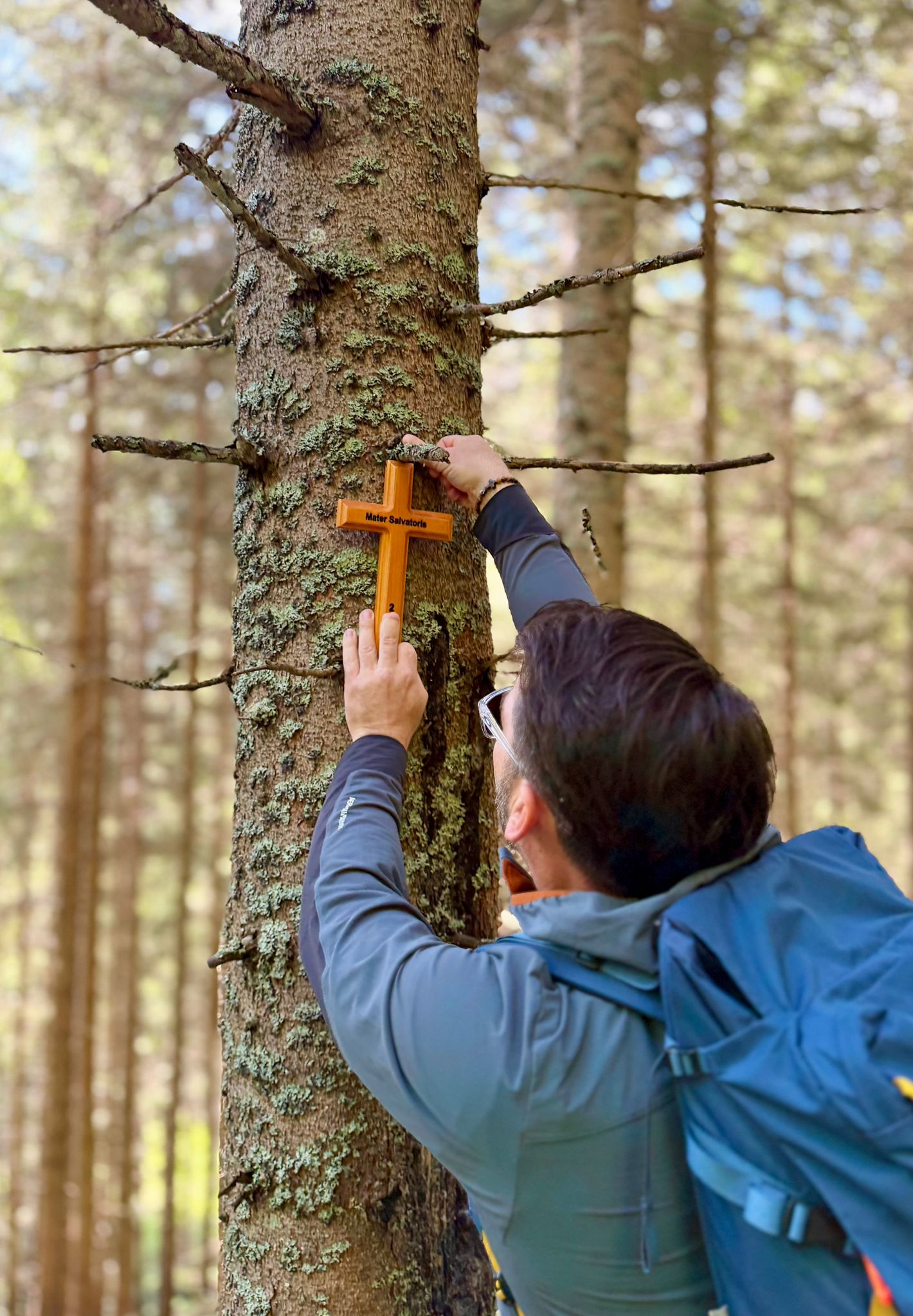 Geschäftsführer Günther Schranz hängt unterwegs ein Holzkreuz auf einem Baum auf