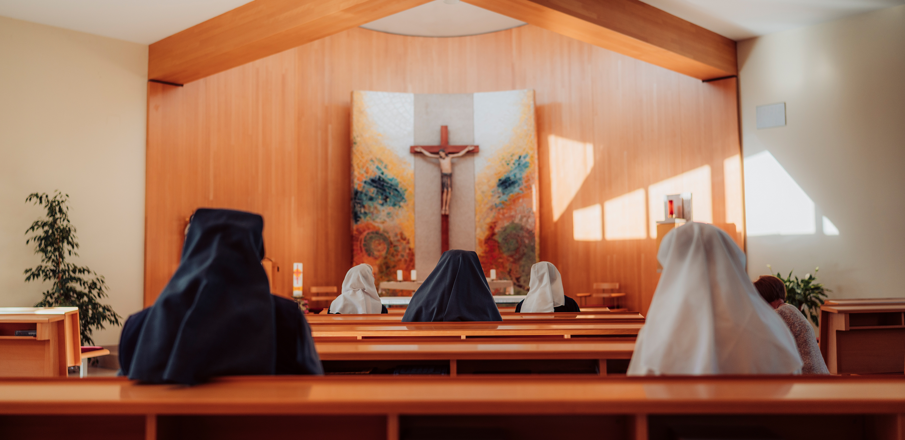 Mehrere Ordensschwester beten in der hellen, modernen Kapelle.