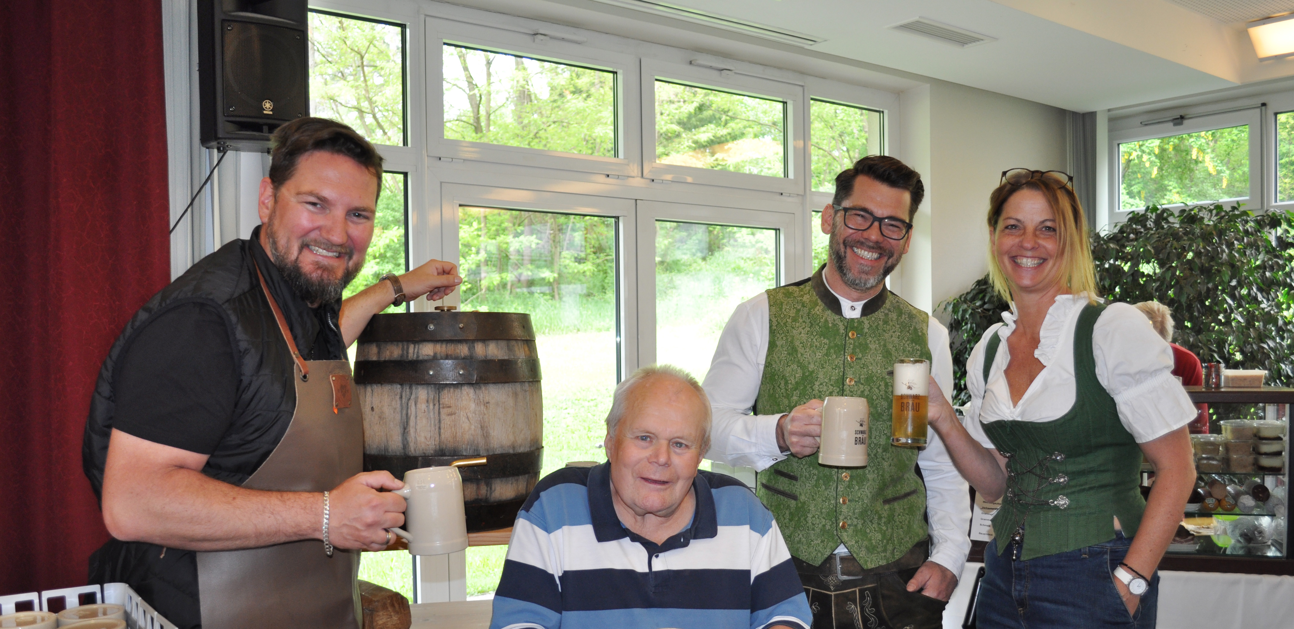 Drei Mitarbeiter des Mater Salvatoris in Tracht stoßen mit einem Bewohner mit Bier an.