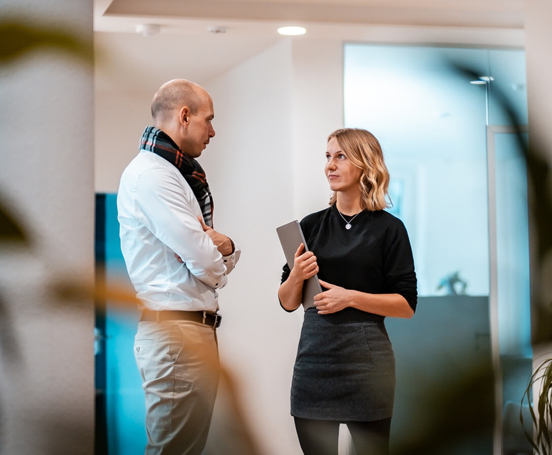 Zwei Personen im Business-Outfit unterhalten sich.