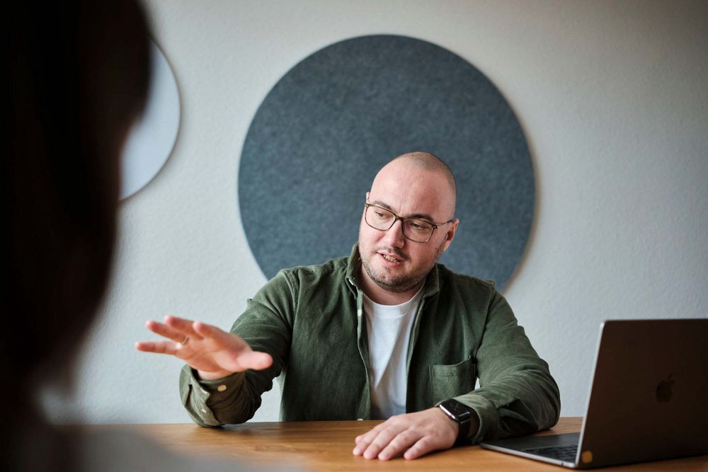 Mann mit Brille erklärt etwas in einer Gesprächsrunde.