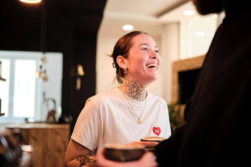 Frau mit Tattoos lacht in einer Büroszene