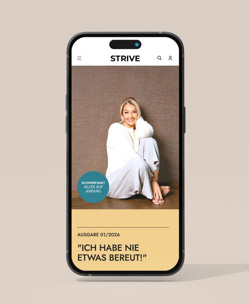 Smartphone displaying a magazine cover with a smiling person in cozy attire, text headline in German: "Ich habe nie etwas bereut!"