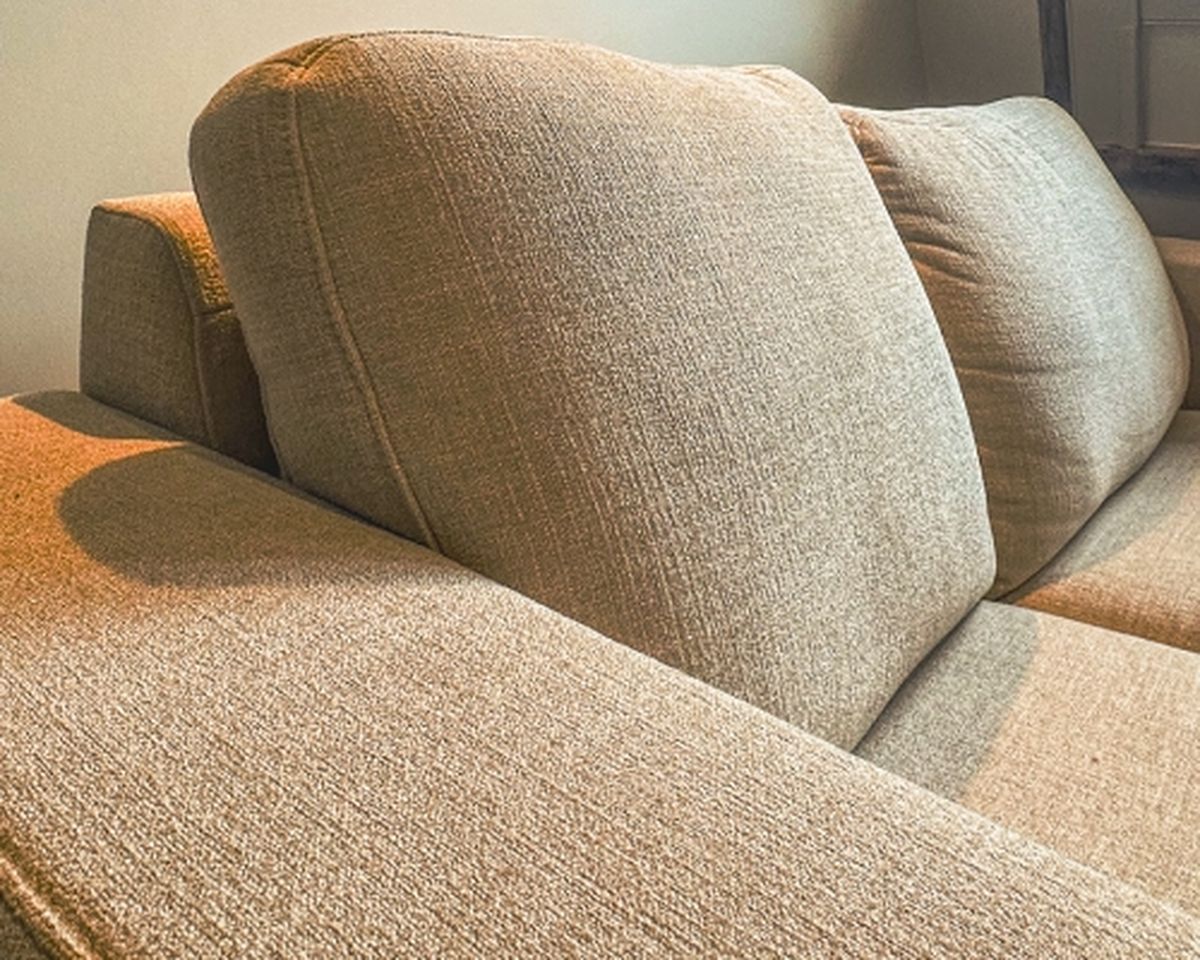 Close-up of a beige fabric sofa showing textured cushions and armrests, with soft lighting creating a cozy ambience.