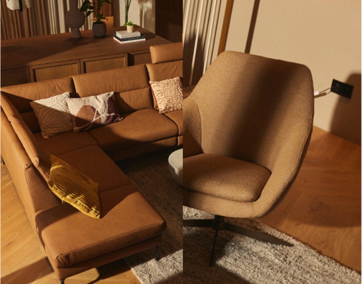 A cozy living room with a brown L-shaped sectional sofa, patterned cushions, a round chair, a textured rug, and plants on a wooden cabinet.