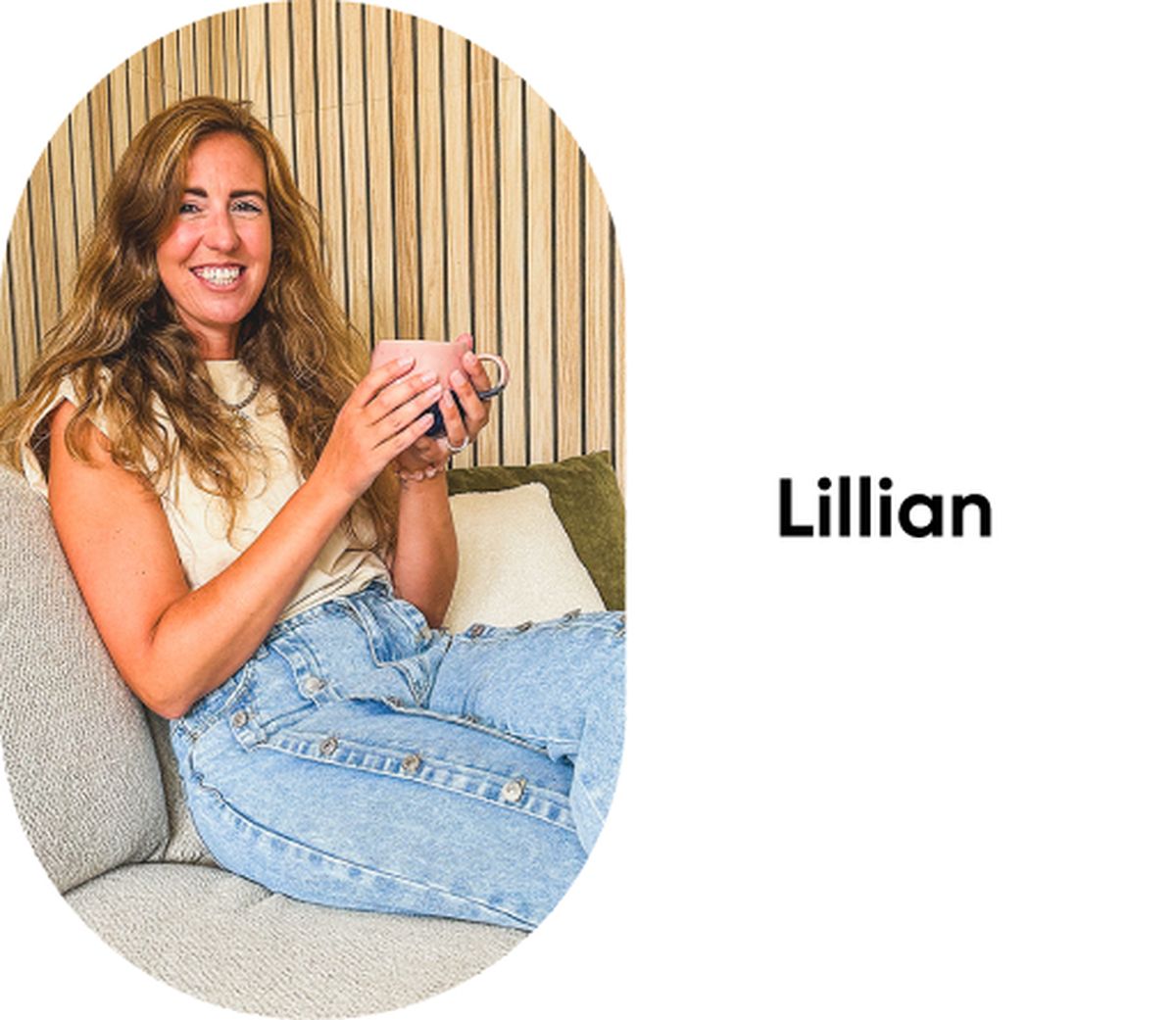 Een vrouw zit op een grijze bank met een kopje in haar hand.