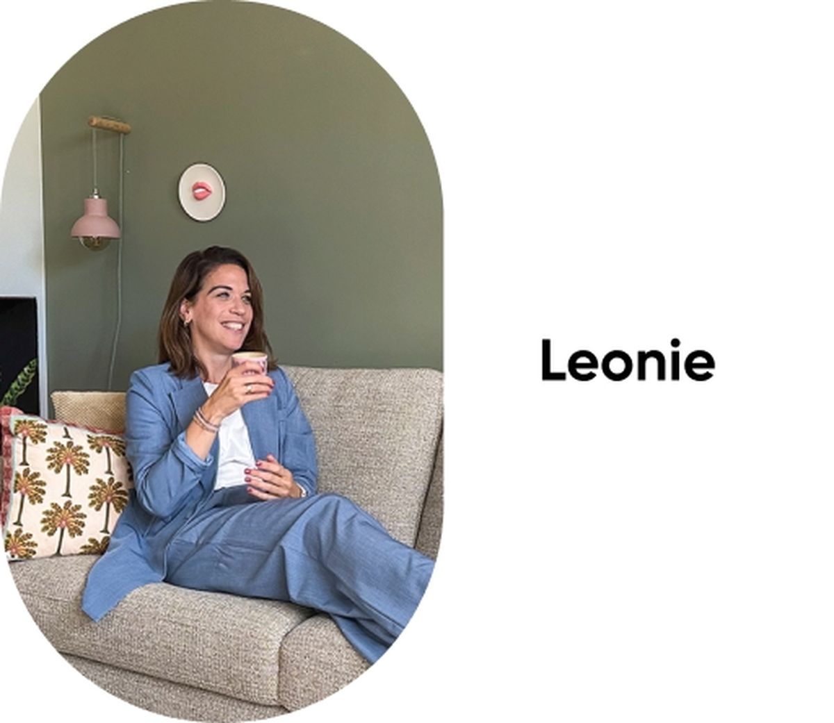 Woman in a blue suit sitting on a beige couch with a patterned pillow, smiling and holding a cup, with the name "Leonie" beside her.