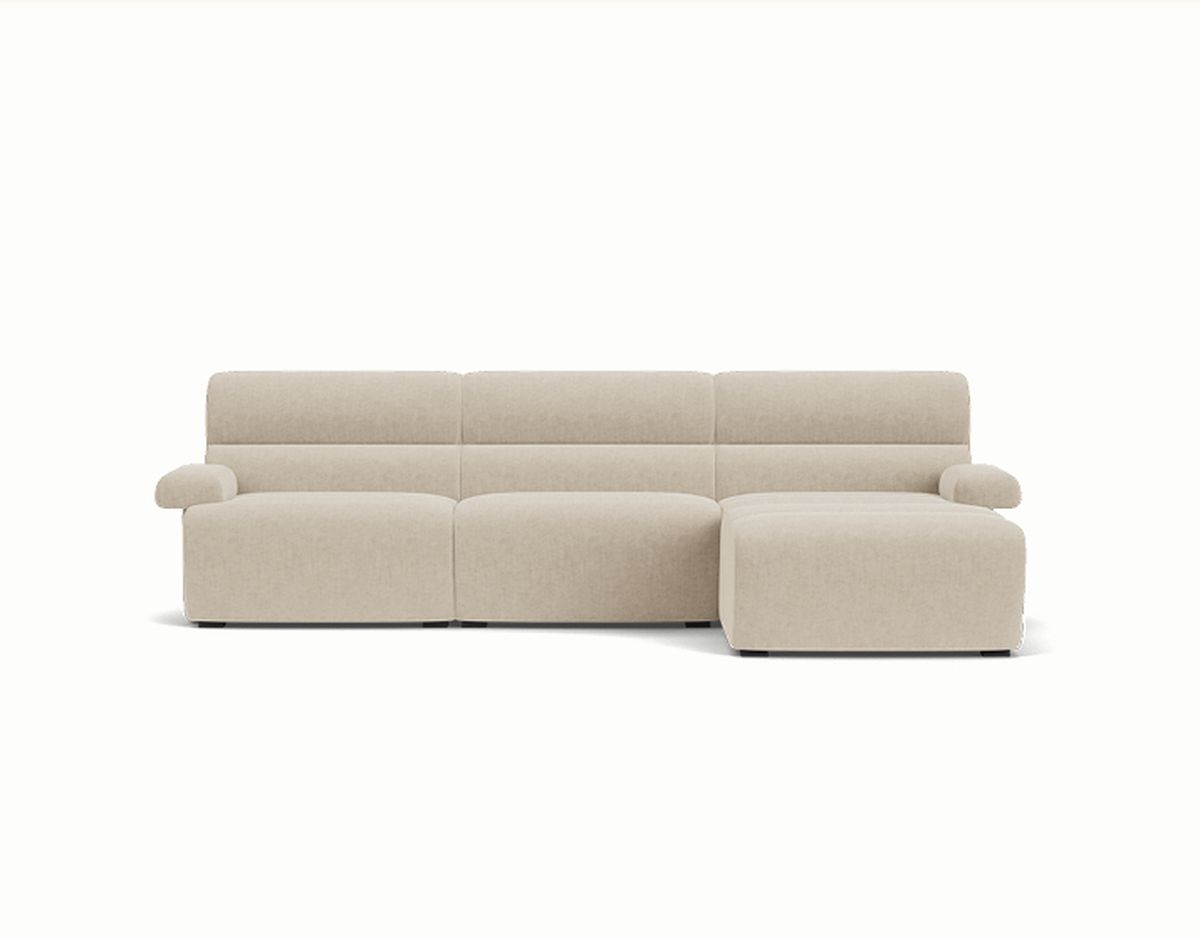 Beige three-seater sectional sofa with chaise on the right side and padded armrests on both ends, set against a white background.