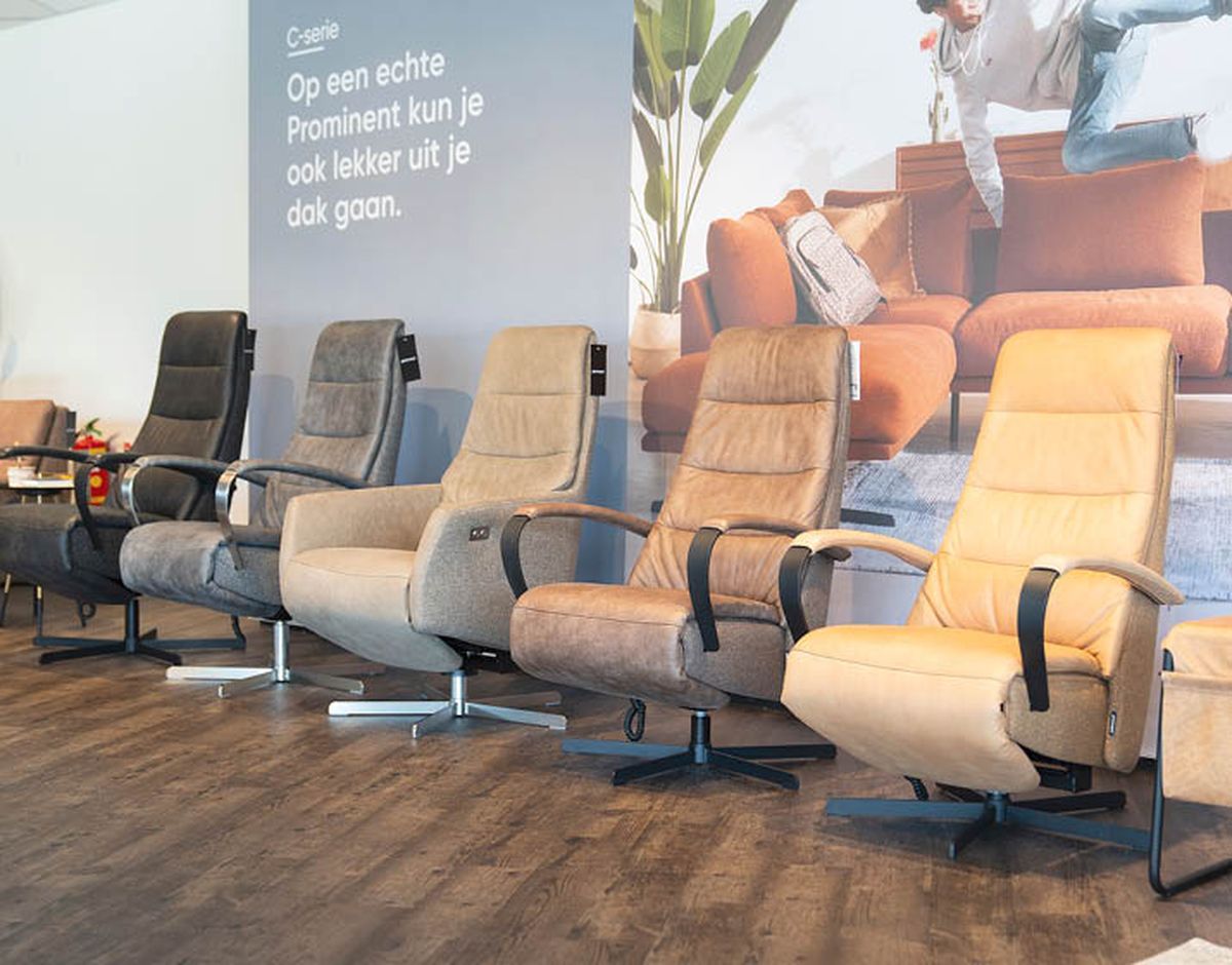 Een rij comfortabele, verstelbare stoelen in verschillende tinten, met een reclameposter op de achtergrond.
