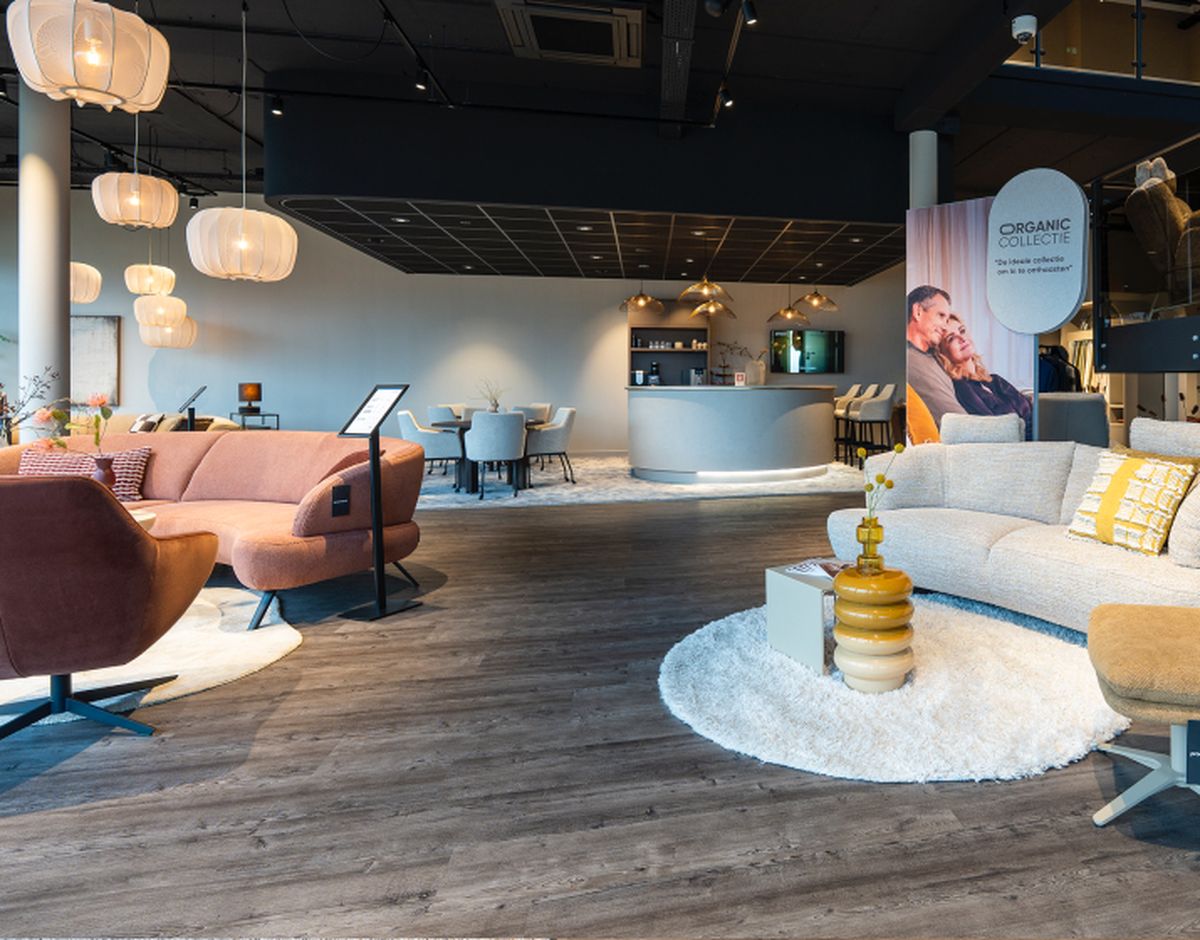 Moderne meubelwinkel met elegante banken, stoelen en tafels. Warme verlichting en houten vloer geven een gezellige en stijlvolle sfeer.
