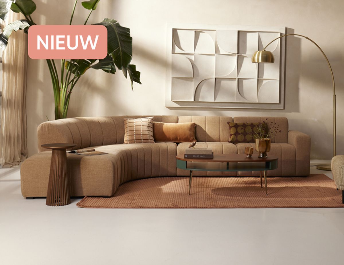 Modern living room with a beige sectional sofa, decorative pillows, a coffee table, gold floor lamp, and abstract wall art. "NIEUW" text in corner.