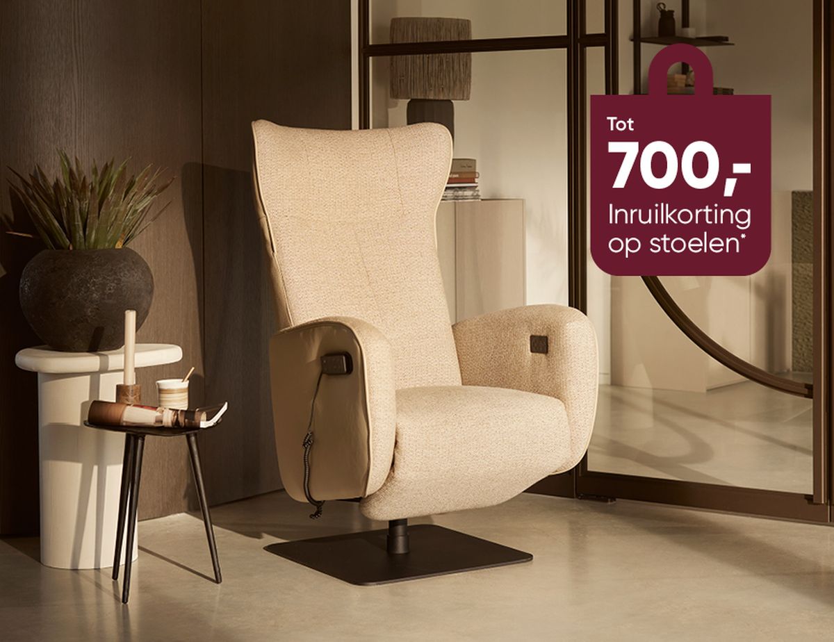 Beige recliner chair in a modern room with a small table, plant, and a discount sign for chairs in the background.