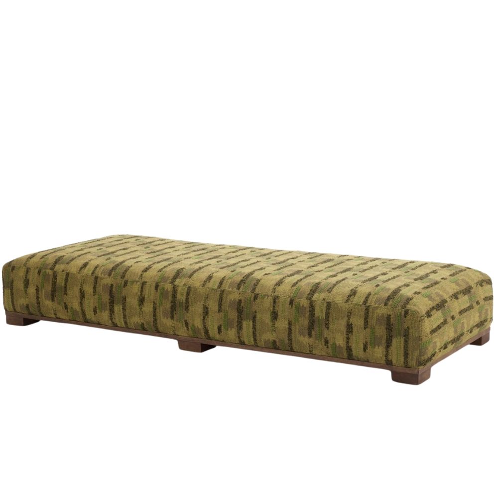 Magnus pouf in a green patterned fabric with low wooden block feet.