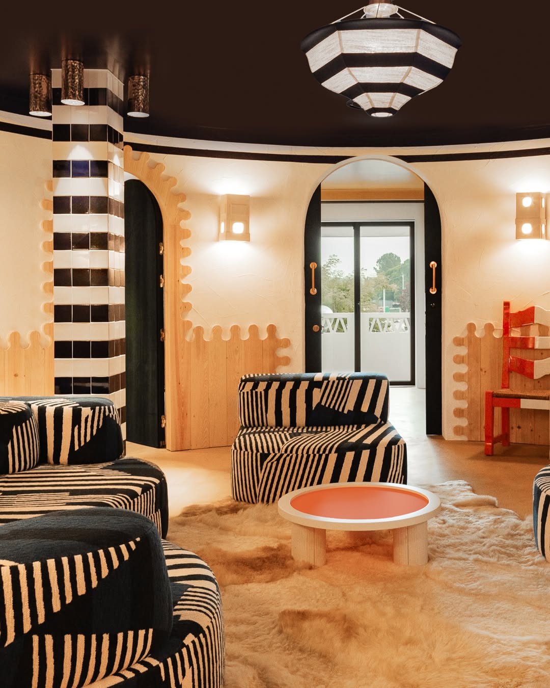 Playful interior of the JNcQUOI Deli Suite in Comporta with bold black-and-white striped seating, warm wood accents, and eclectic decor.