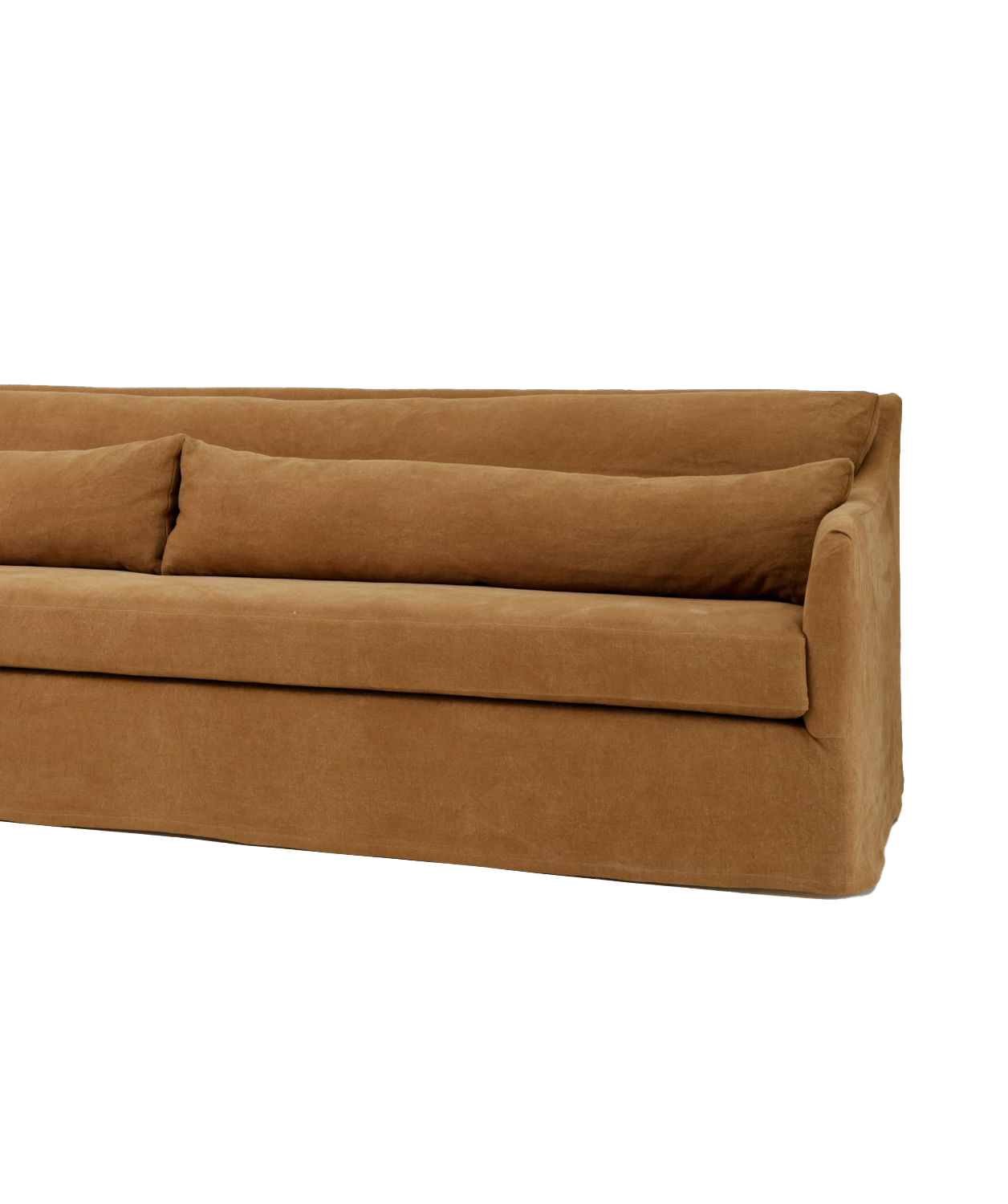 A close-up image of a long, low-profile sofa with a minimalist design. The sofa features two long cushions placed on the backrest, all covered in a soft, warm-toned fabric.