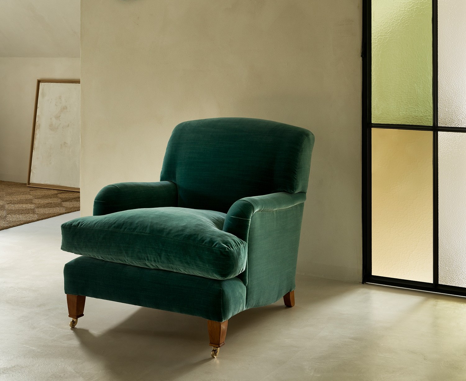 Hecto armchair with loose seat cushion in deep green velvet, classic design with wooden legs.