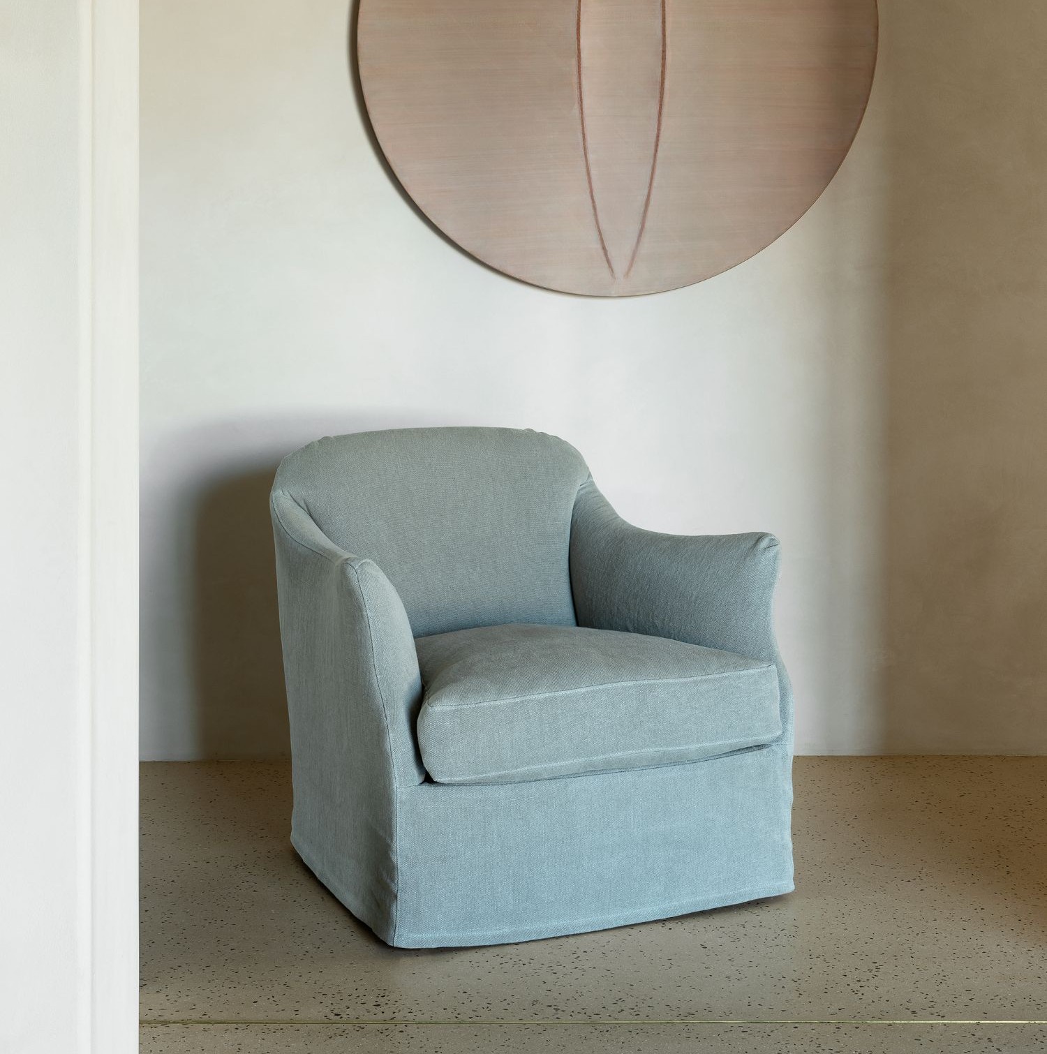 Camille armchair by Collett & Victor in soft blue fabric, elegant curved design with fitted slipcover, styled in a minimal interior.