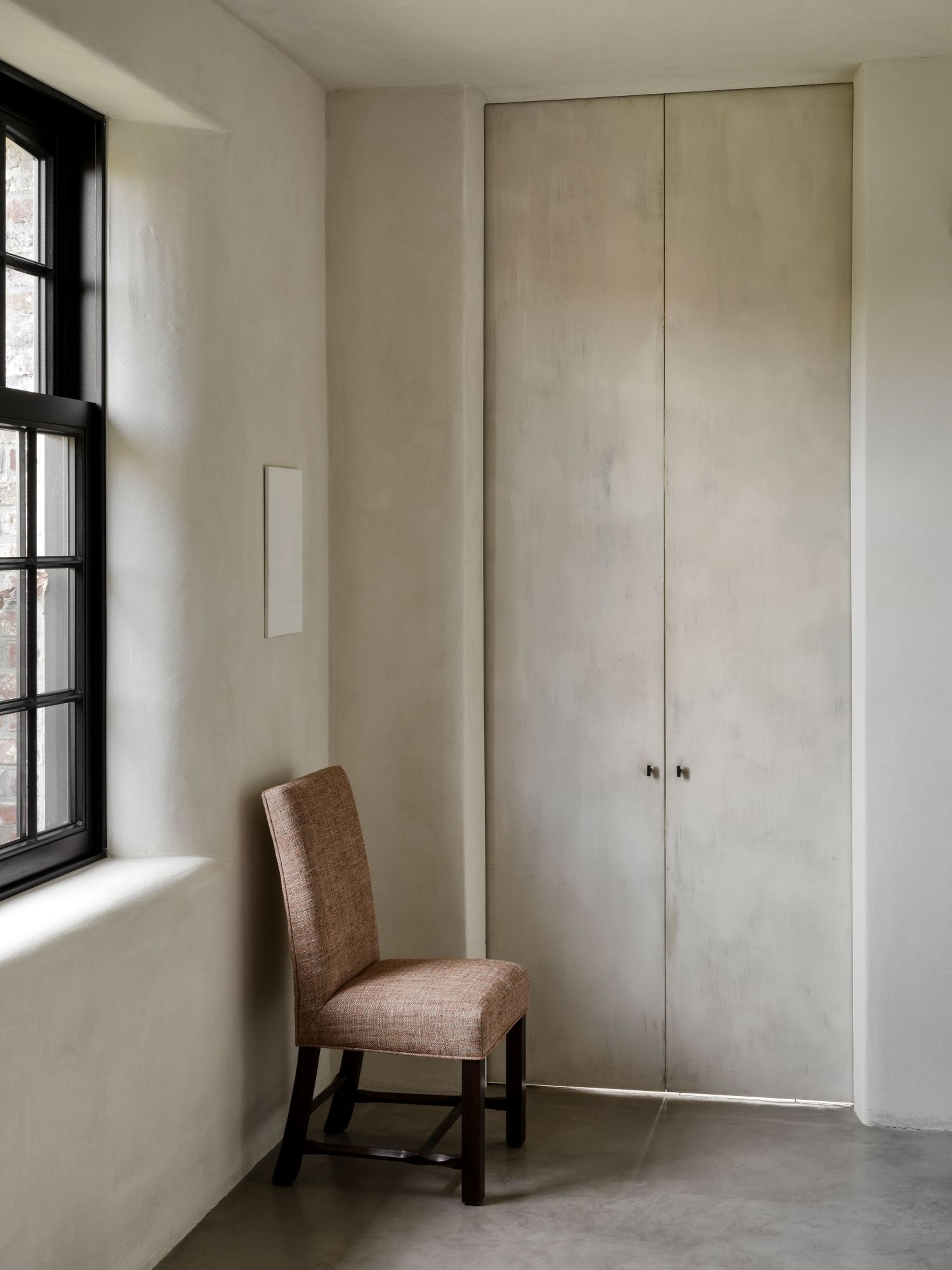 Maya dining chair without armrests by Collett & Victor, upholstered in warm brown fabric with dark wooden legs, shown in a minimalist interior.