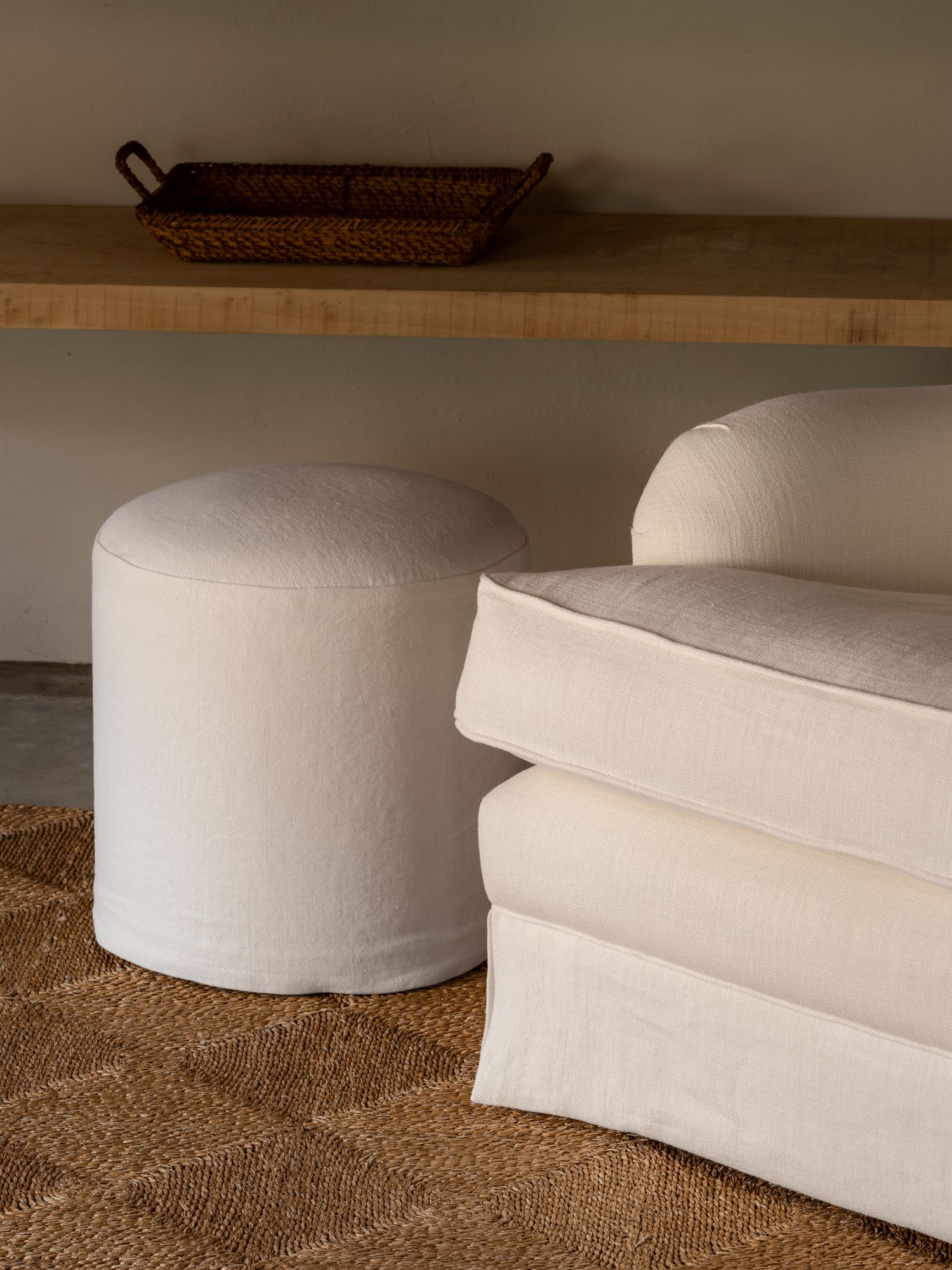 Minimalist Rozy pouf by Collett & Victor in white fabric, styled next to an armchair on a woven rug for a natural interior look