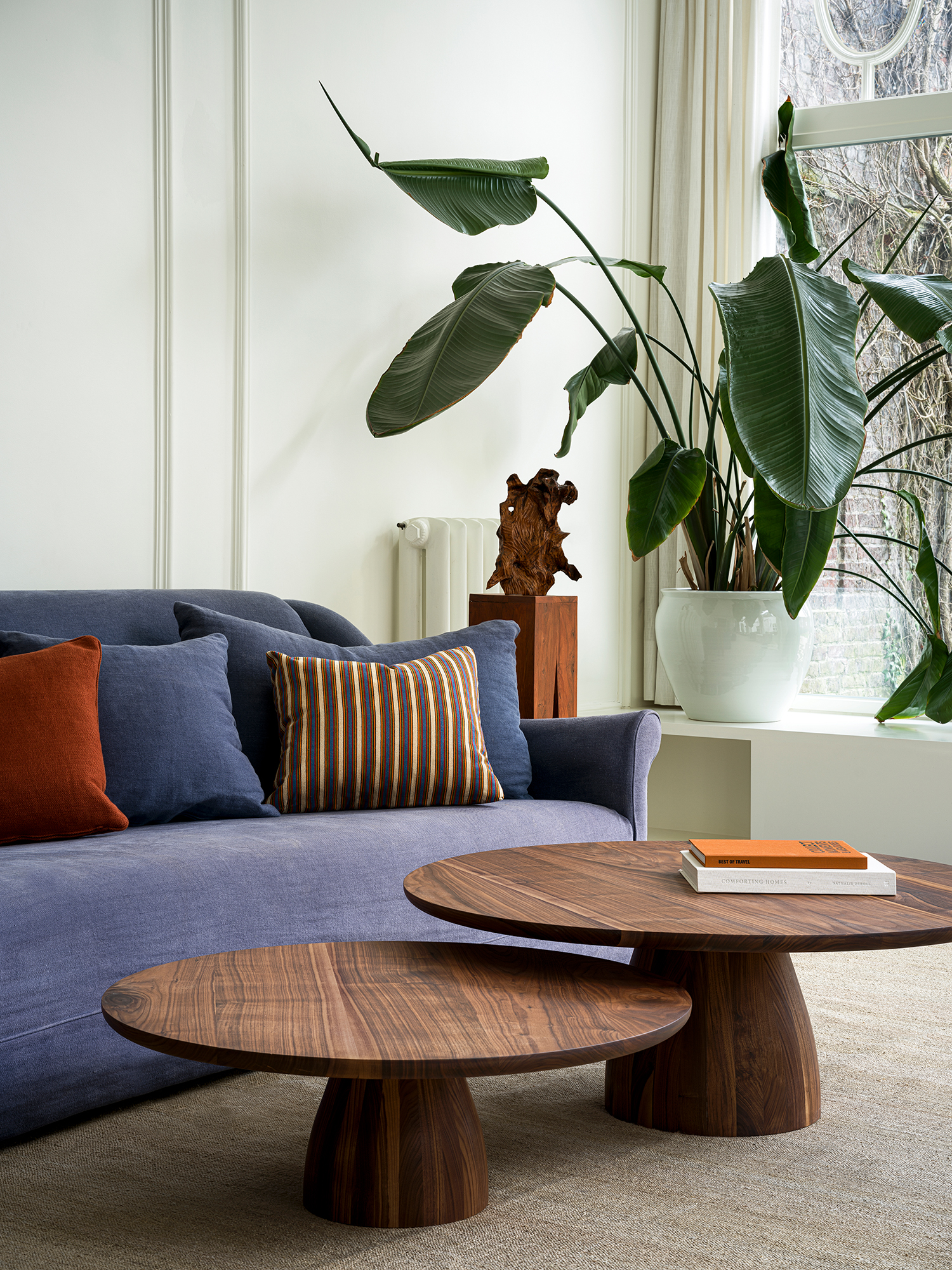 Close-up of the Nova coffee tables in solid walnut, showing rich wood grain detail with books styled on the tabletop.