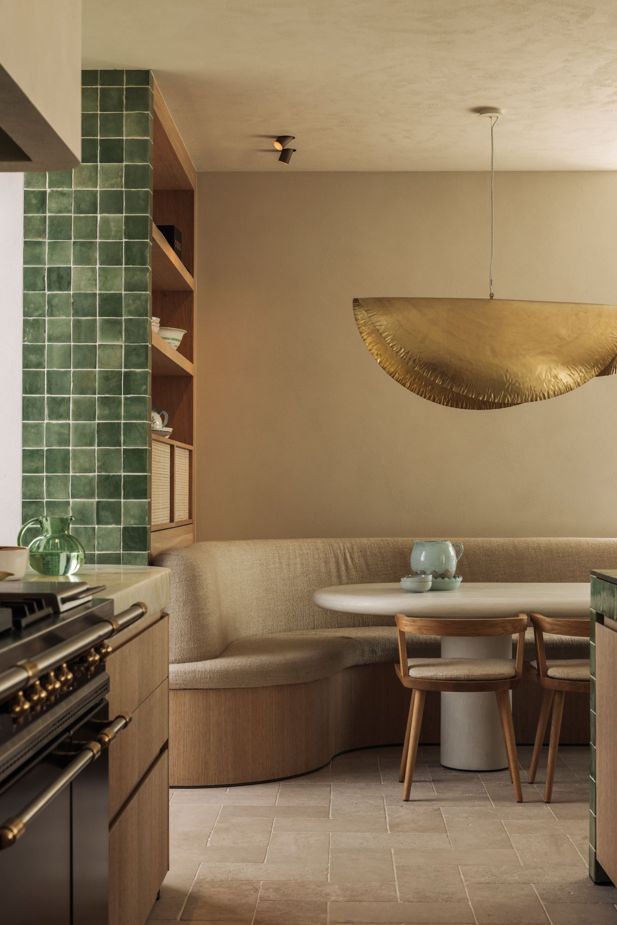 Contemporary kitchen with bespoke upholstered banquette by Collett & Victor, paired with natural textures and a striking brass pendant.