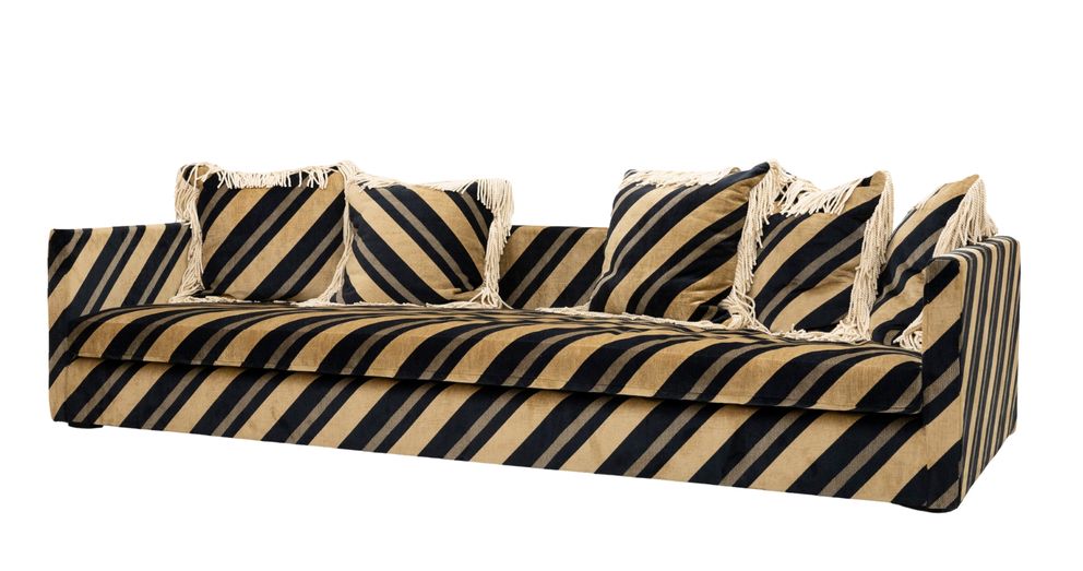 The Trancoso sofa with bold black and beige diagonal striped upholstery and five throw pillows with fringe details.