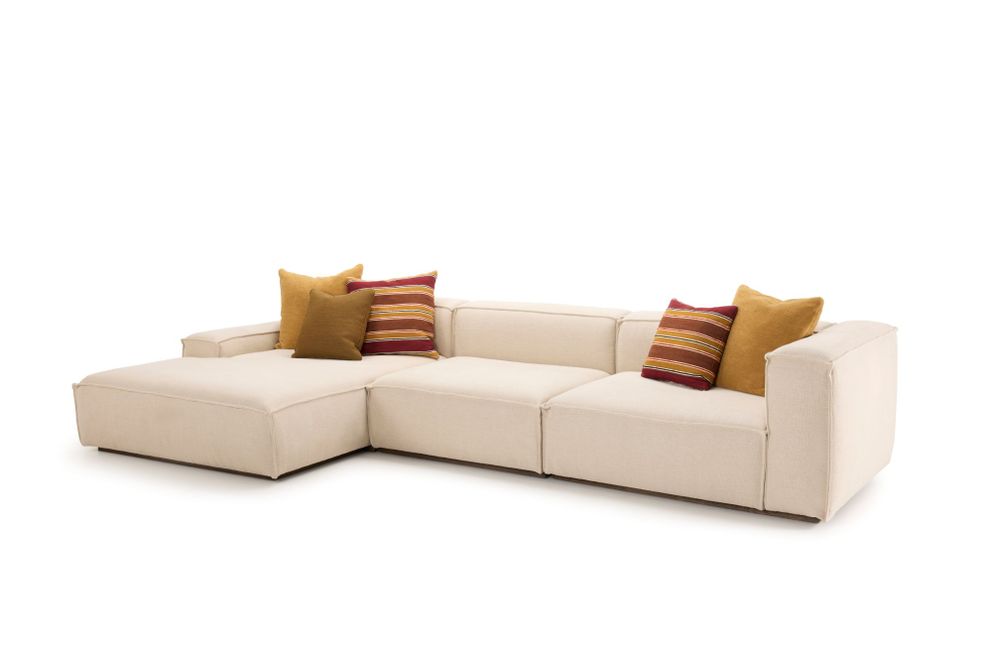 Modular sectional sofa in off-white fabric with low-profile arms and backrest, arranged in an L-shape, accented with mustard yellow and striped red cushions.