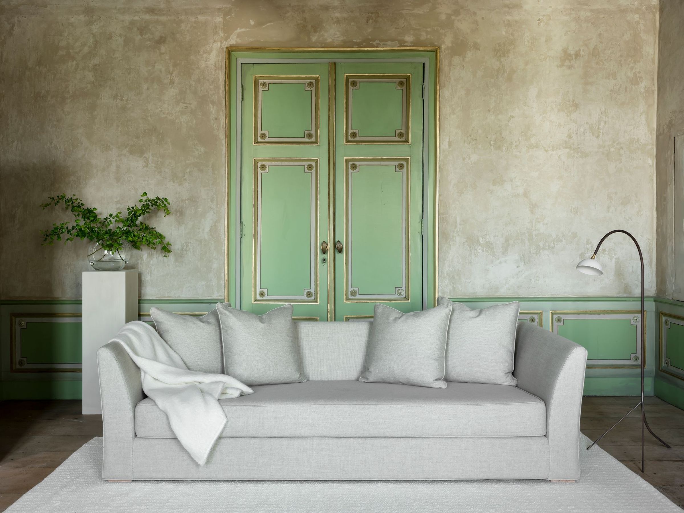 New York sofa in light grey with two cushions and a white throw blanket.