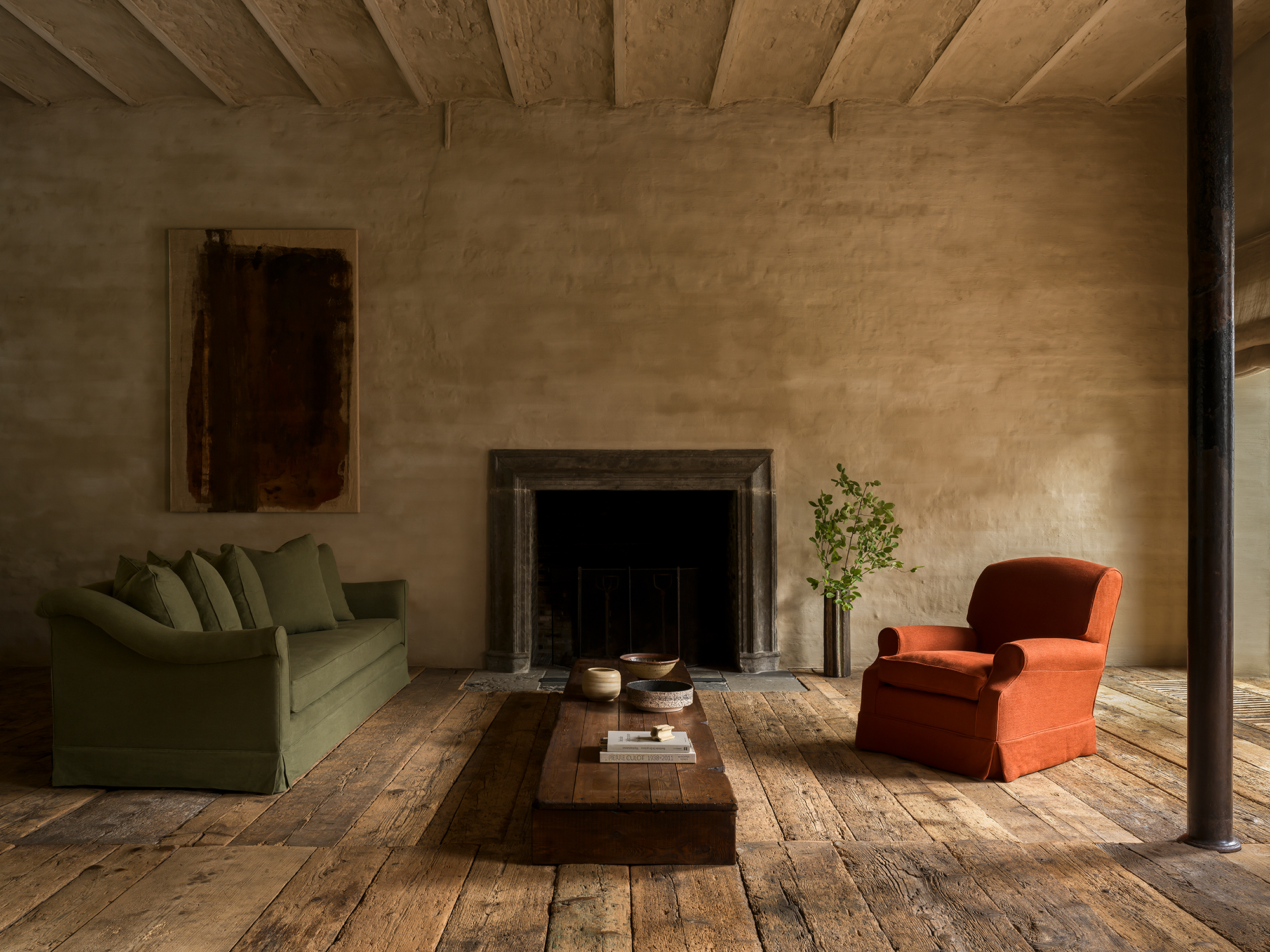 Collett & Victor rustic living room with Borbado sofa, orange armchair, stone fireplace and wooden floors.