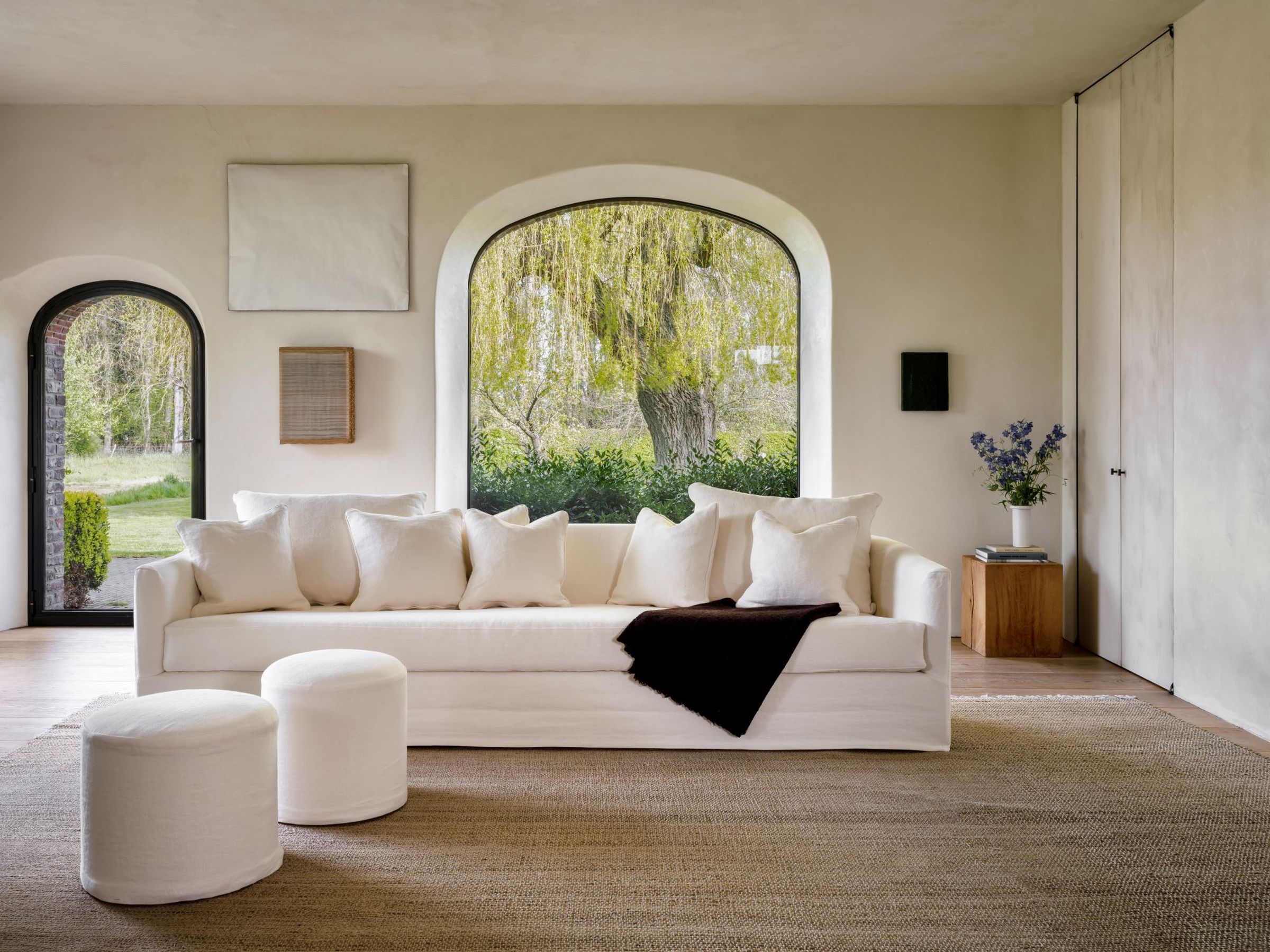 Minimalist living room with white sofa and two Rozy poufs in linen fabric.