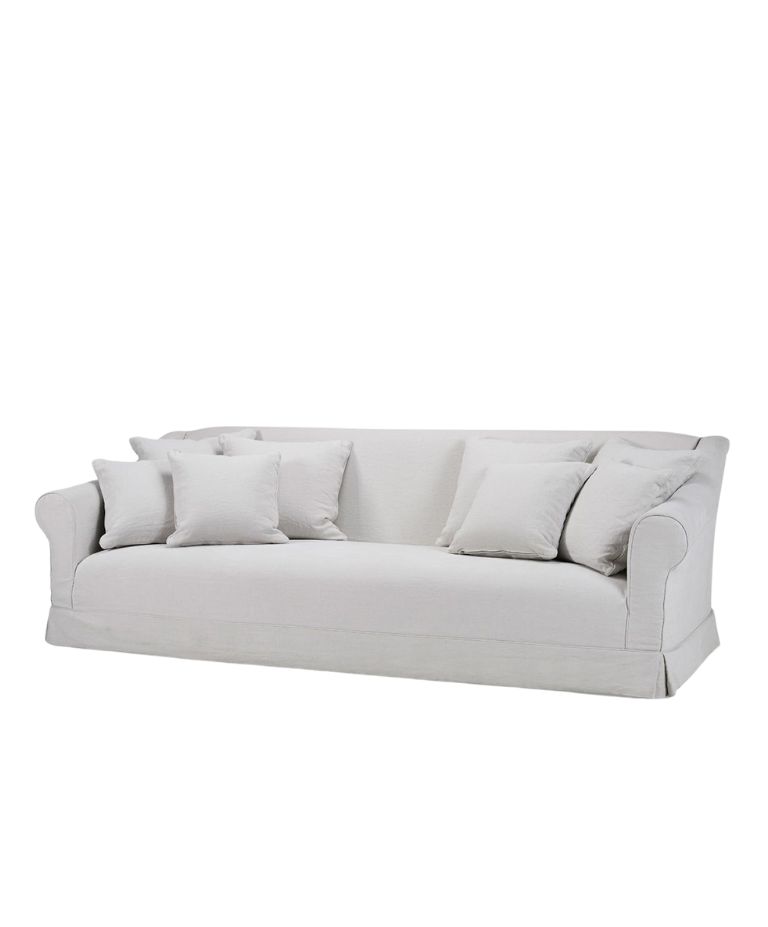Barbara sofa in soft off-white fabric with classic rolled arms, a tailored skirt, and multiple matching scatter cushions for a relaxed, elegant look.